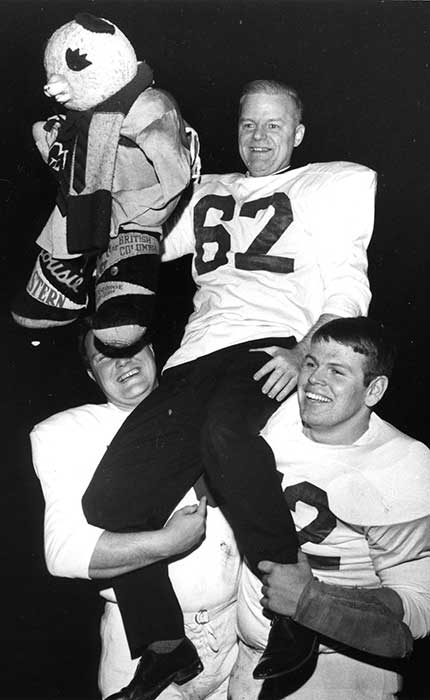 Father Guindon on the shoulders of two Gee-Gees football players