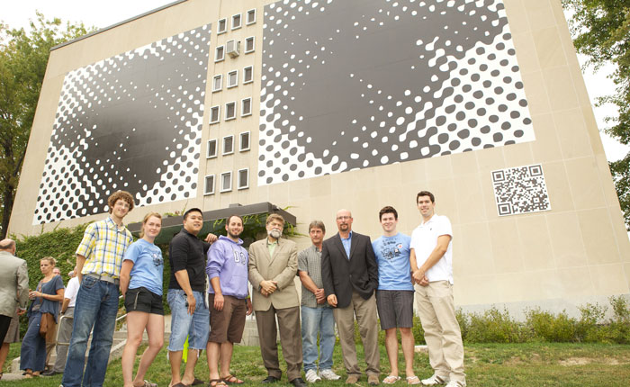 André Lalonde, surrounded by group of students who got together to restore the Les Yeux murale. The group is standing in front of the restored mural.
